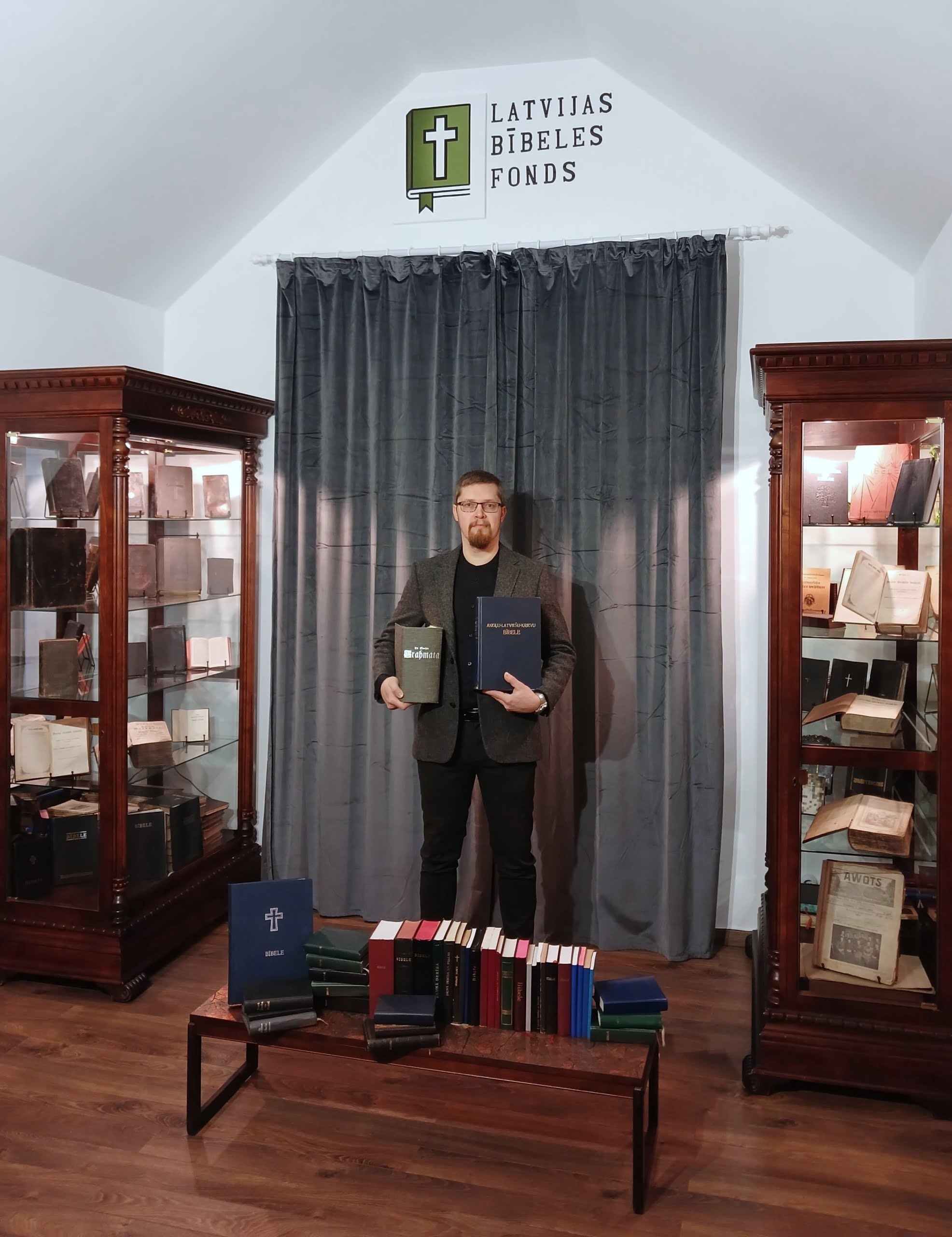 Latvijas Bībeles Fonda dibinātājs un valdes priekšsēdētājs Andris Bušs-Boss LBF mītnē ar latviešu Bībeļu kolekciju
